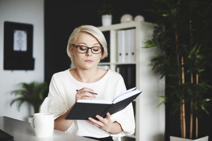 Focused woman writing on a notebook at her office Focused woman writing on a notebook at her office